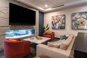 a living room with couches and chairs and a television at The Clearing at ONE28, Olathe, KS
